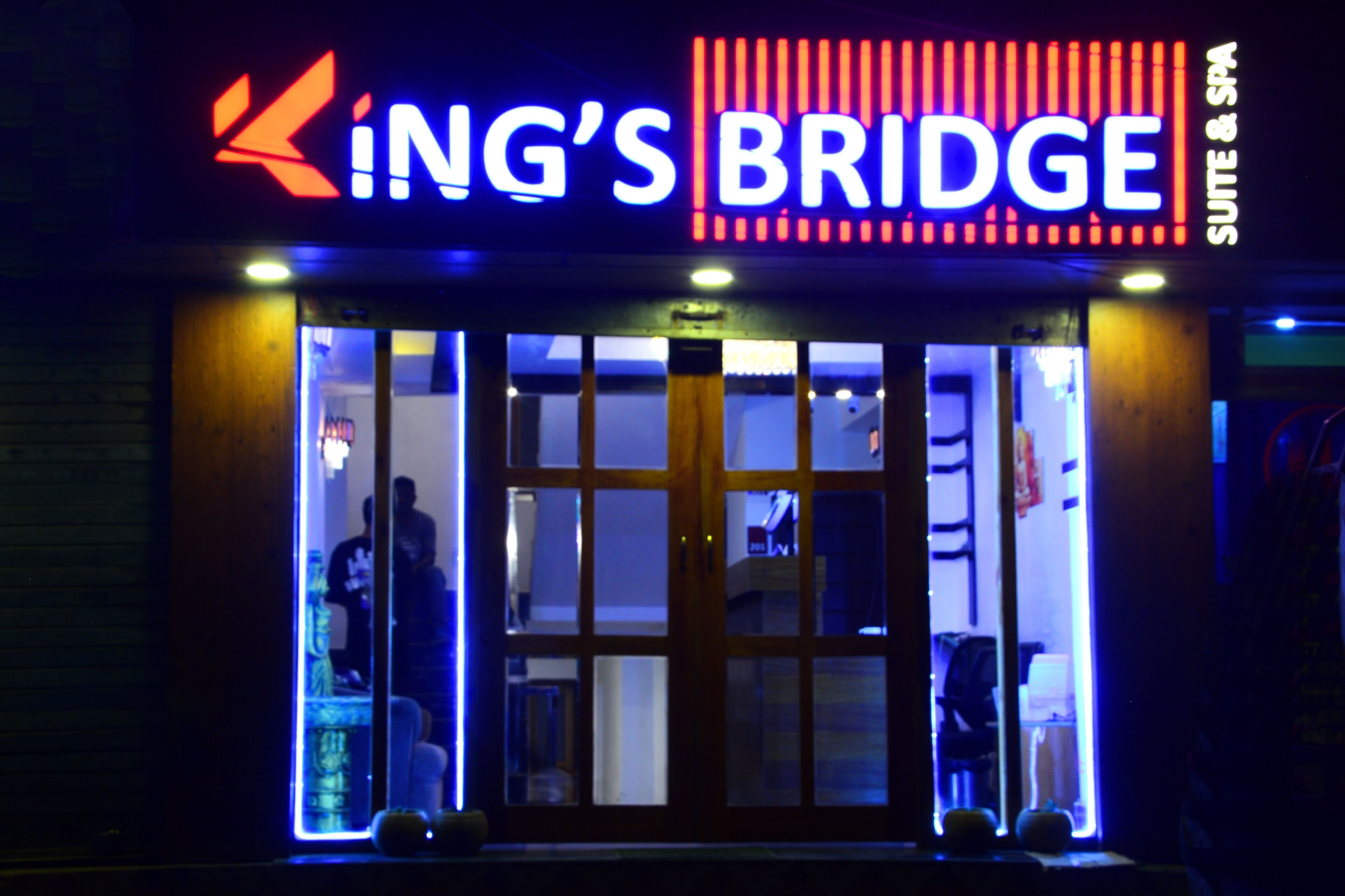 A hotel entrance with a neon sign reading "King's Bridge" and a visible door.