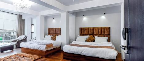 Habitación de hotel moderna con dos camas, un candelabro, un ventanal grande y vistas a la ciudad.