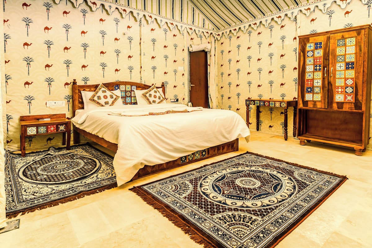 A bedroom with a bed, two nightstands, a wooden wardrobe, and patterned carpets.