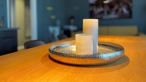 A dining table with a glass candle holder and candles. - InkBlue Apartment (Heidenau)