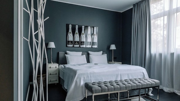 A modern bedroom with a large bed, bedside tables, a bench, and a wall-mounted artwork. - InkBlue Apartment (Heidenau)