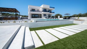 A modern two-story house with a swimming pool, outdoor seating, and a well-maintained lawn.
