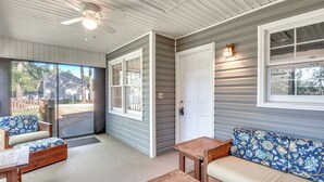 A covered porch with a ceiling fan, a wooden bench, a cushioned sofa, and a small table. - Screened Patio & Yard: Clemson Weekends/lakes Stay (Seneca)