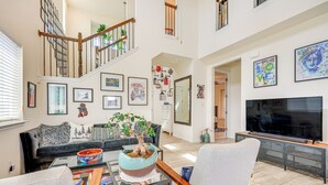 A spacious living room with a staircase, a large TV, and various framed artworks on the walls. - Large Fenced Yard: Family-friendly Kyle Home (Kyle)