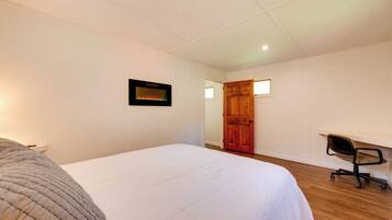 A bedroom with a bed, a desk, and a chair.