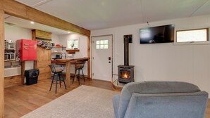 Una habitación acogedora con techo de madera, un refrigerador rojo, un televisor, una chimenea y una zona de comedor con una mesa y sillas de madera.