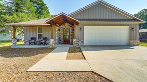 A two-story house with a stone facade, a garage, and a covered porch with outdoor furniture. - Spacious Heber Springs Home - Easy Marina Access! (Heber Springs)
