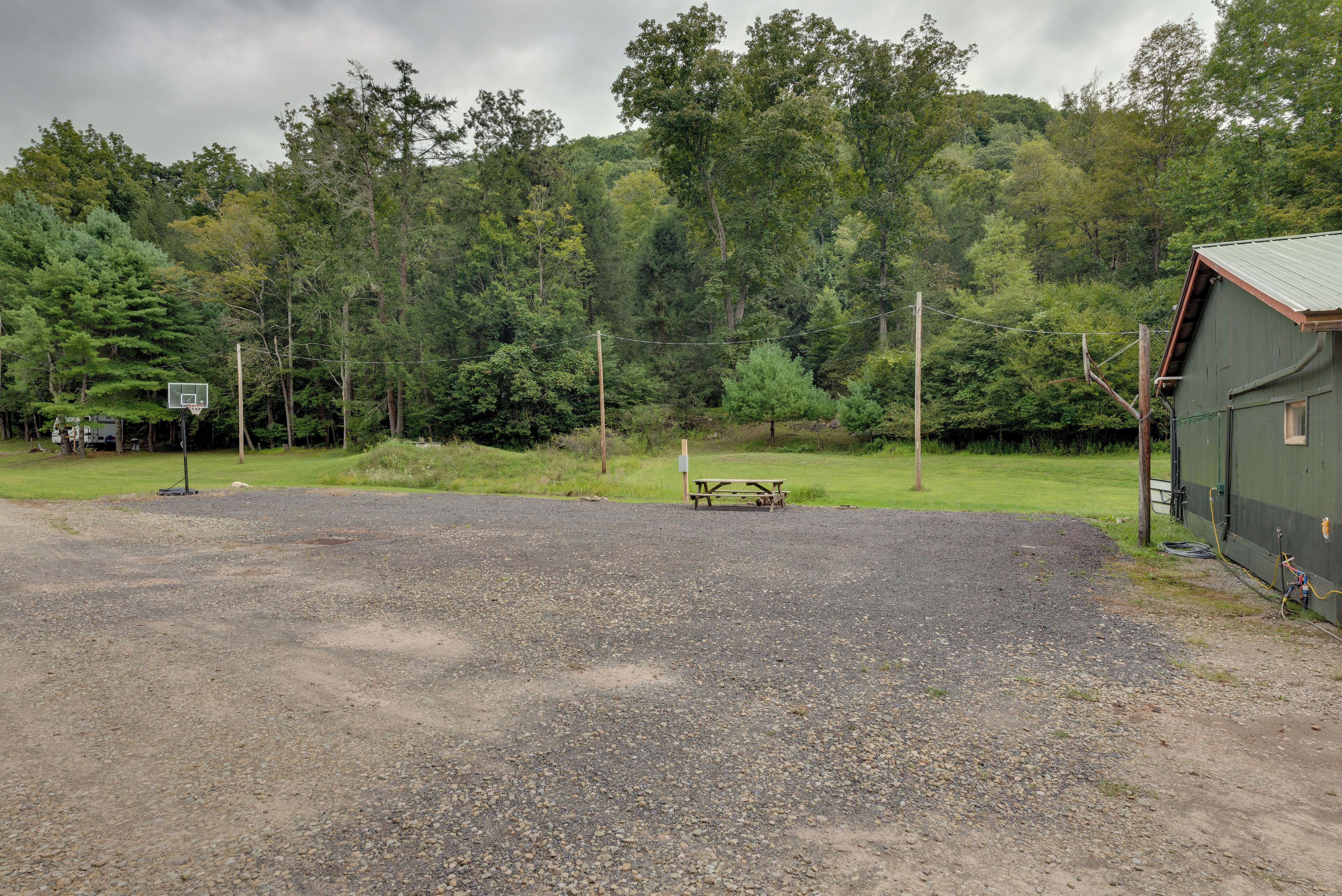 A gravel parking area with a picnic table and basketball hoop.
