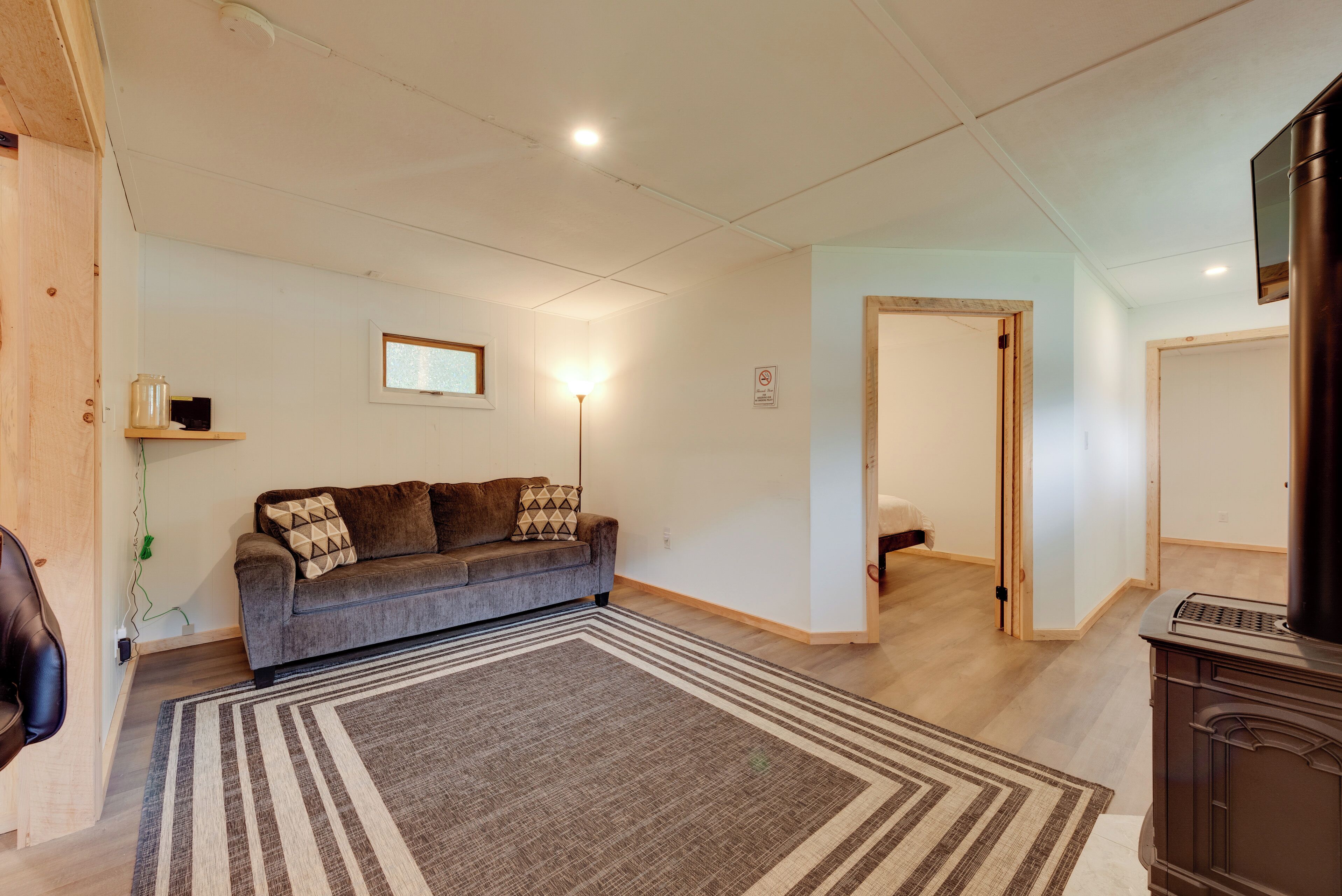 Een woonkamer met een bank, een vloerkleed, een televisie en een open haard.