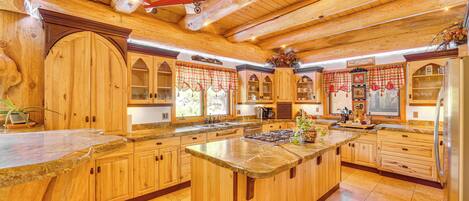 Una cocina amplia con armarios de madera, una isla grande y un techo alto con vigas a la vista.
