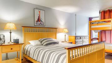 Un dormitorio con una cama de madera, dos mesitas de noche con lámparas, un aparador y una cama literera, además de un póster en la pared.
