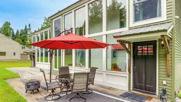 Une terrasse avec une table et des chaises, un parasol rouge et un pot décoratif en métal.
