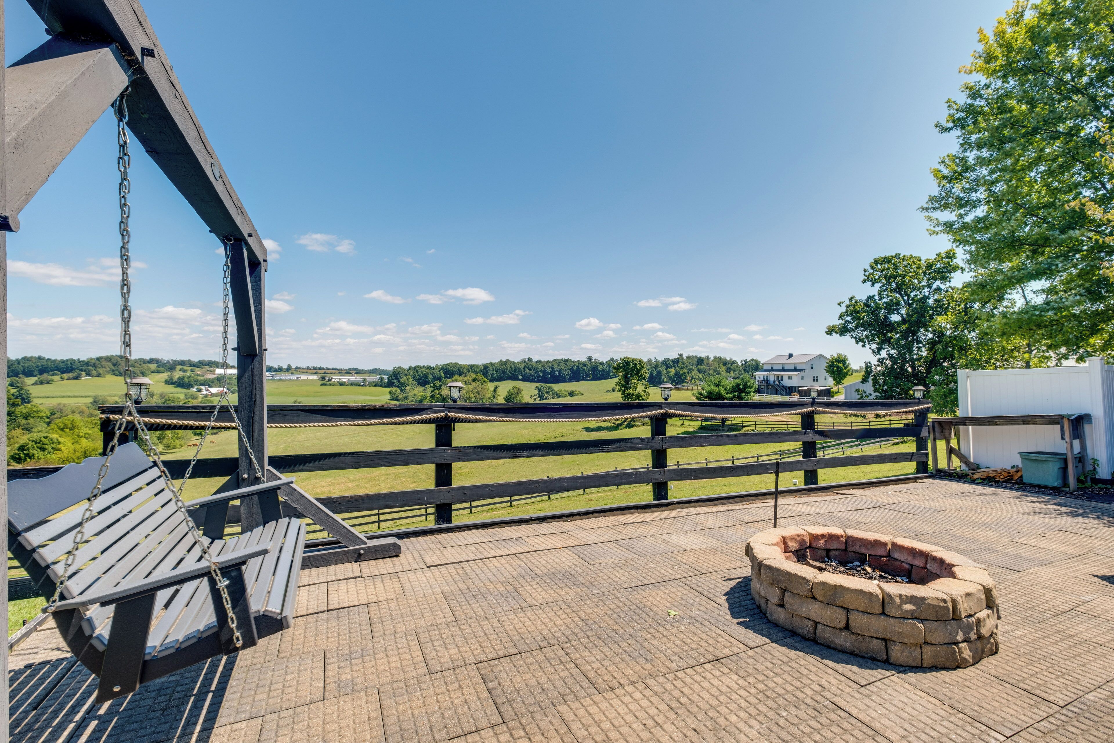 Une terrasse avec une balançoire, un foyer extérieur et une vue sur un paysage verdoyant.