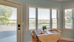Un comedor con mesa, sillas y vistas a un espacio exterior vallado a través de amplios ventanales.