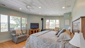 Un dormitorio con una cama grande, televisor, chimenea y ventana con persianas.