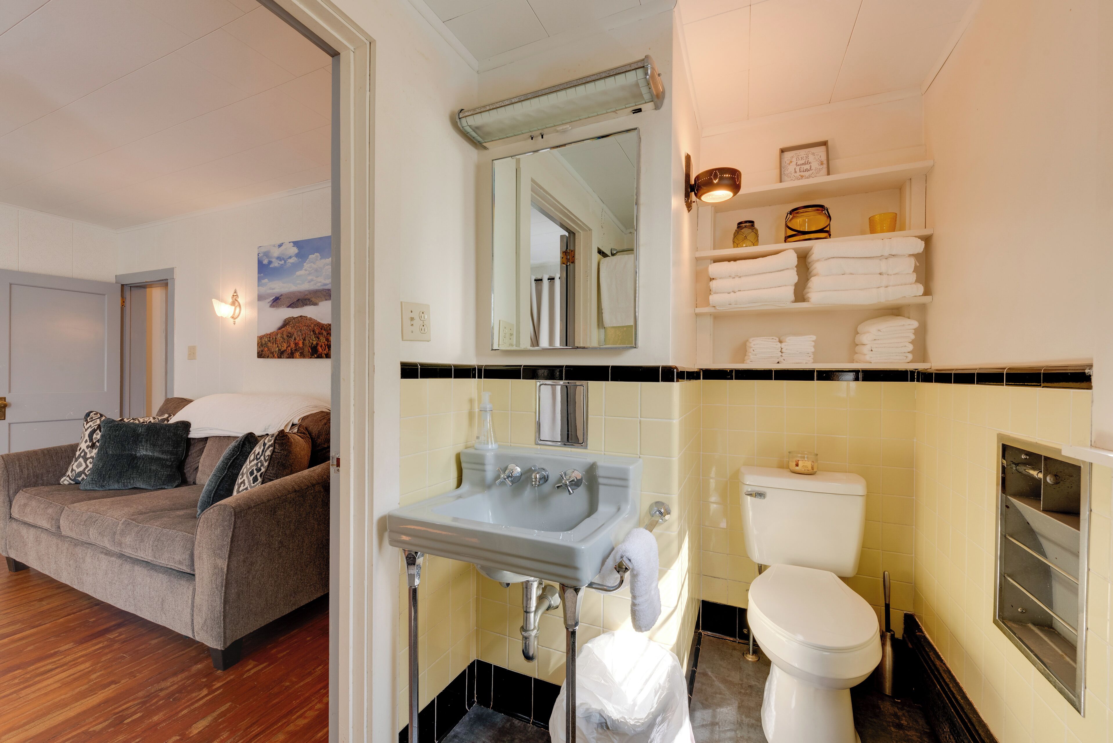 A bathroom with a sink, toilet, and shelves with towels.