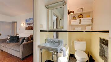 A bathroom with a sink, toilet, and shelves with towels.