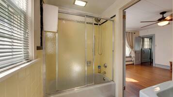 A bathroom with a glass-enclosed shower, a bathtub, and a toilet.