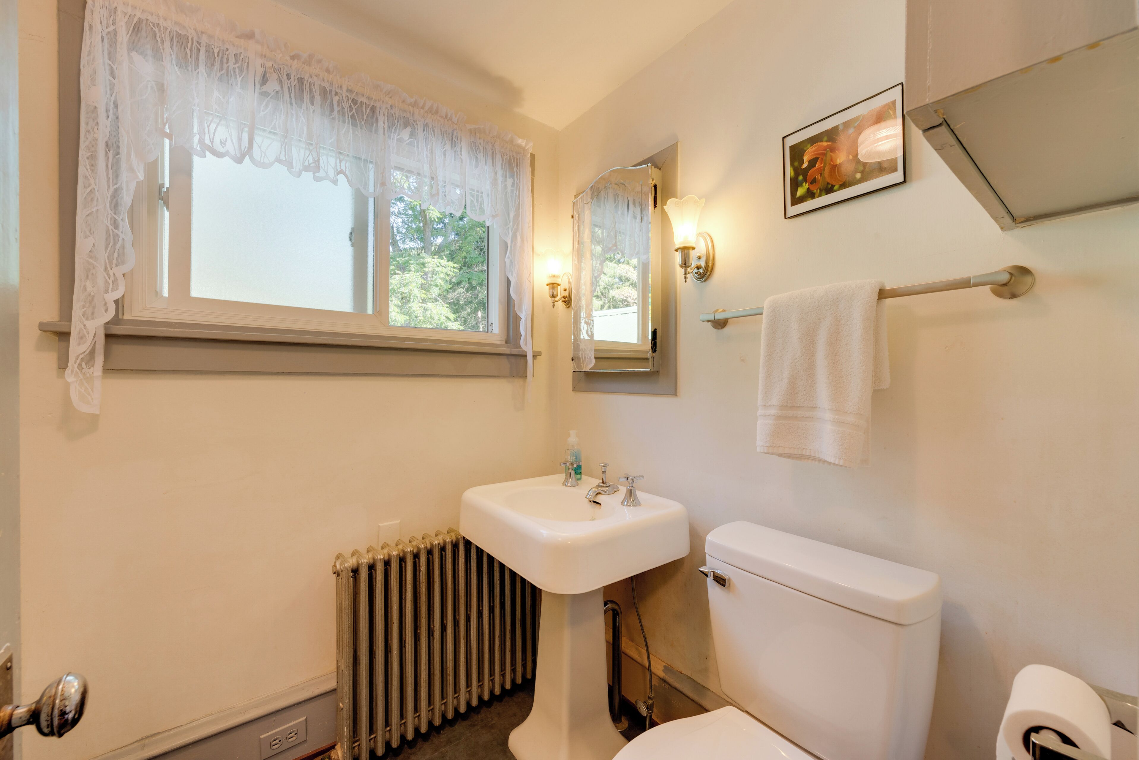 A bathroom with a white sink, toilet, and radiator.