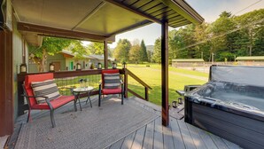 Une terrasse extérieure couverte, équipée d’un jacuzzi, de deux chaises et d’une petite table.