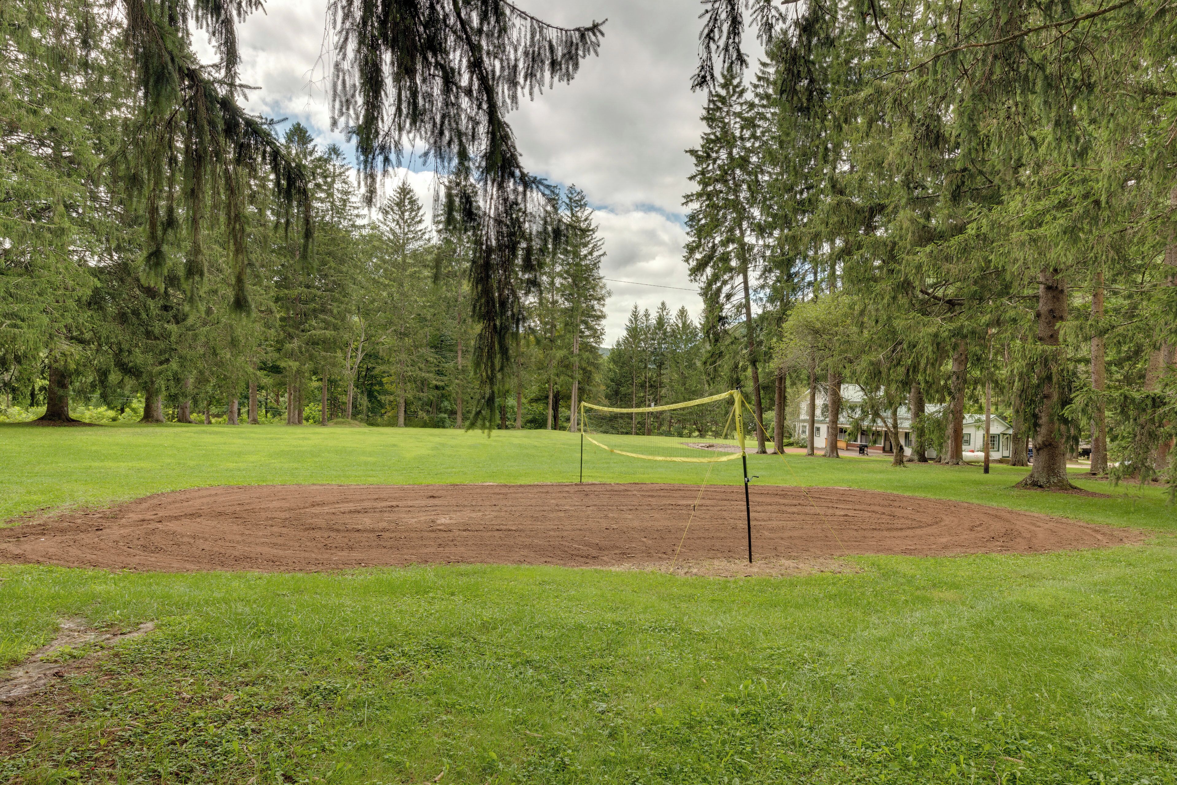 Un campo da baseball con un interno in terra battuta e zone erbose circostanti, circondato da alberi alti.