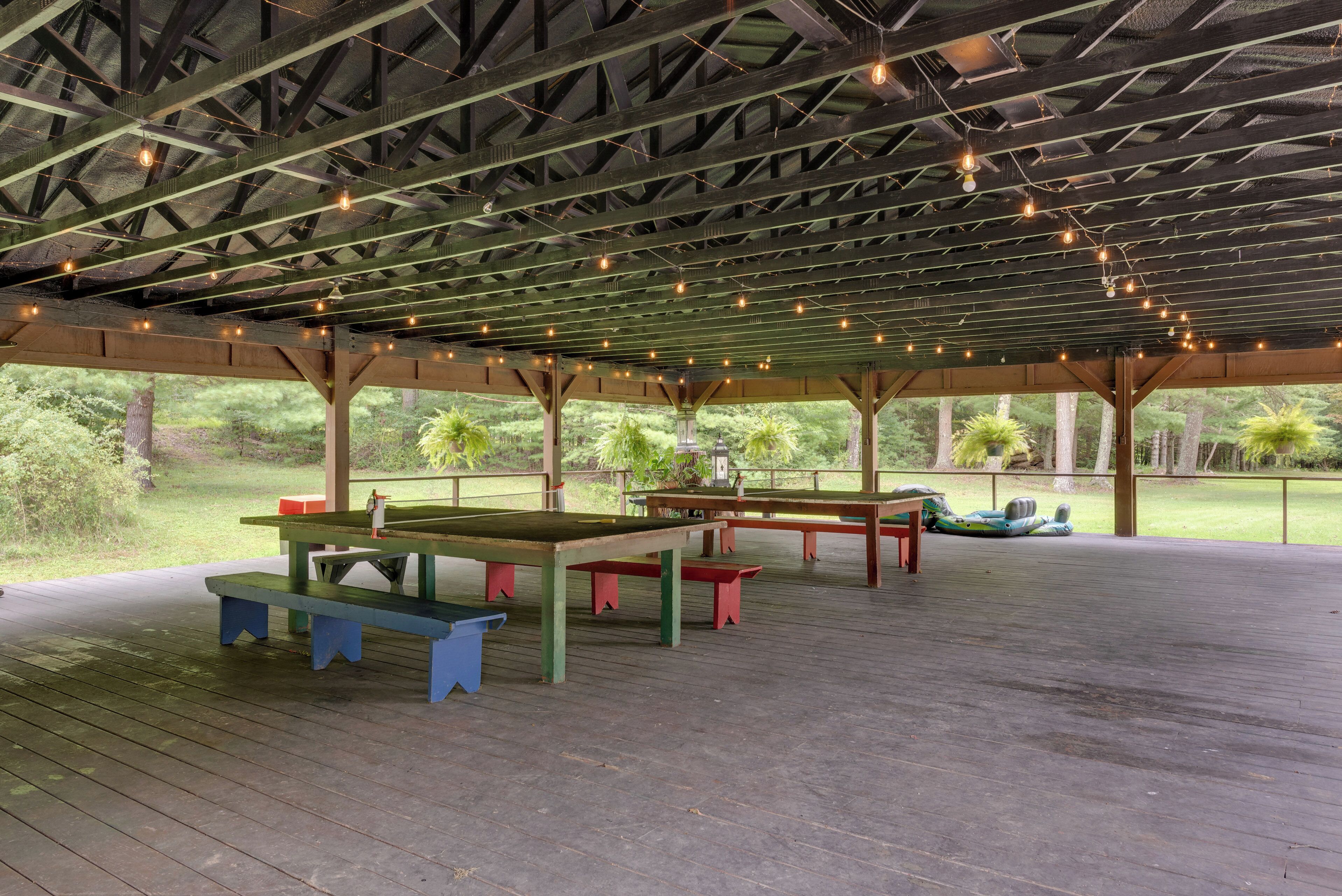 Un pabellón al aire libre con mesas de picnic y luces colgantes.