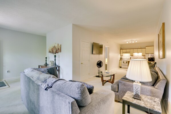 A living room with a grey sofa, a coffee table, and a lamp. There is a door leading to a kitchen in the background. - Basye Getaway w/ Pool Access, 2 Mi to Bryce Resort (Basye)