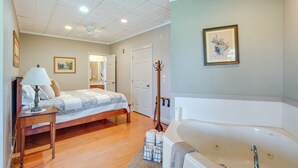 A bedroom with a bed, bedside table, lamp, and a large bathtub. - 'holmes With a View' Studio: Millersburg Retreat! (Millersburg)