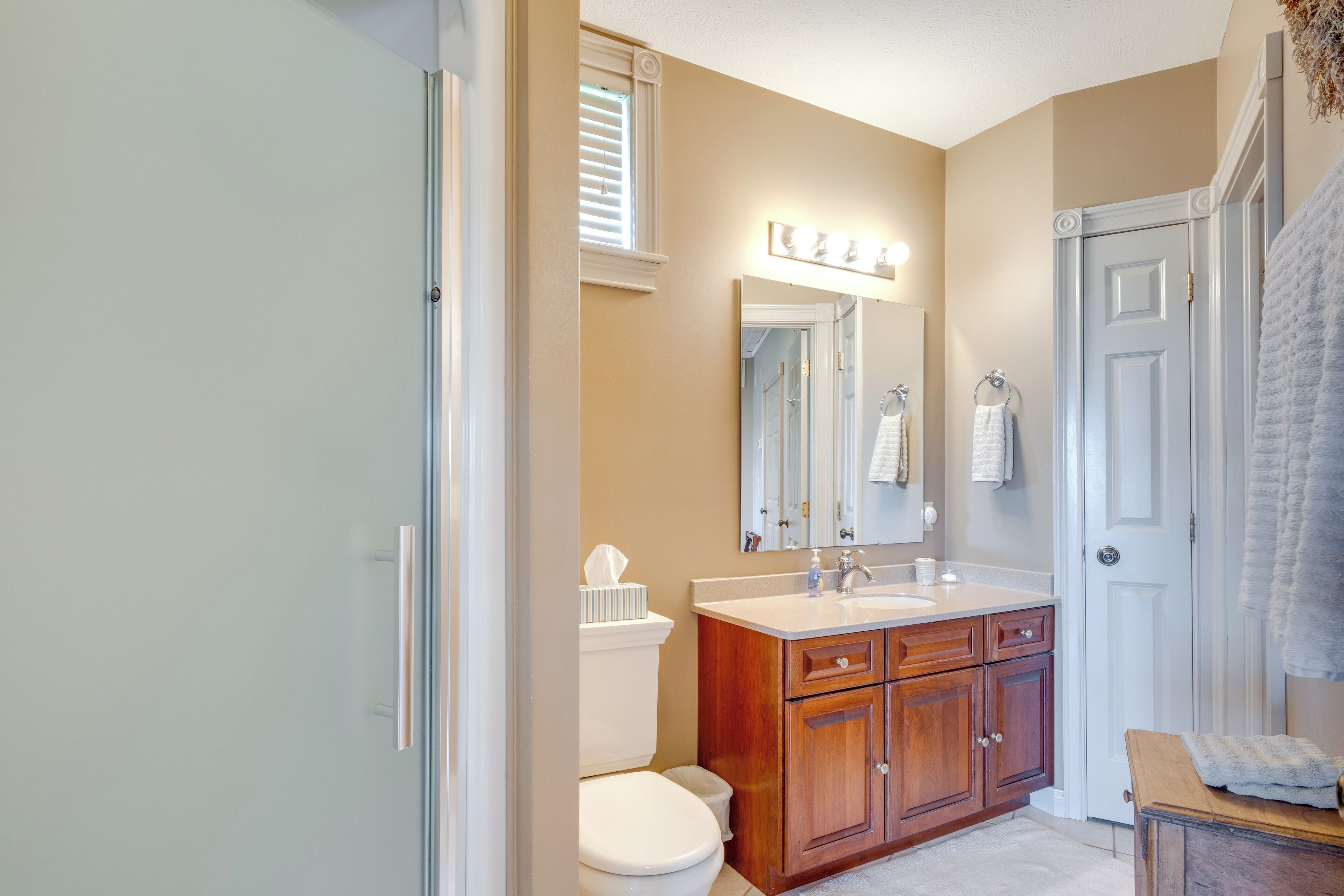 A bathroom with a toilet, vanity, mirror, and towel rack.