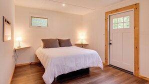 Une chambre à coucher avec un lit, deux lampes de chevet, une fenêtre et une porte.