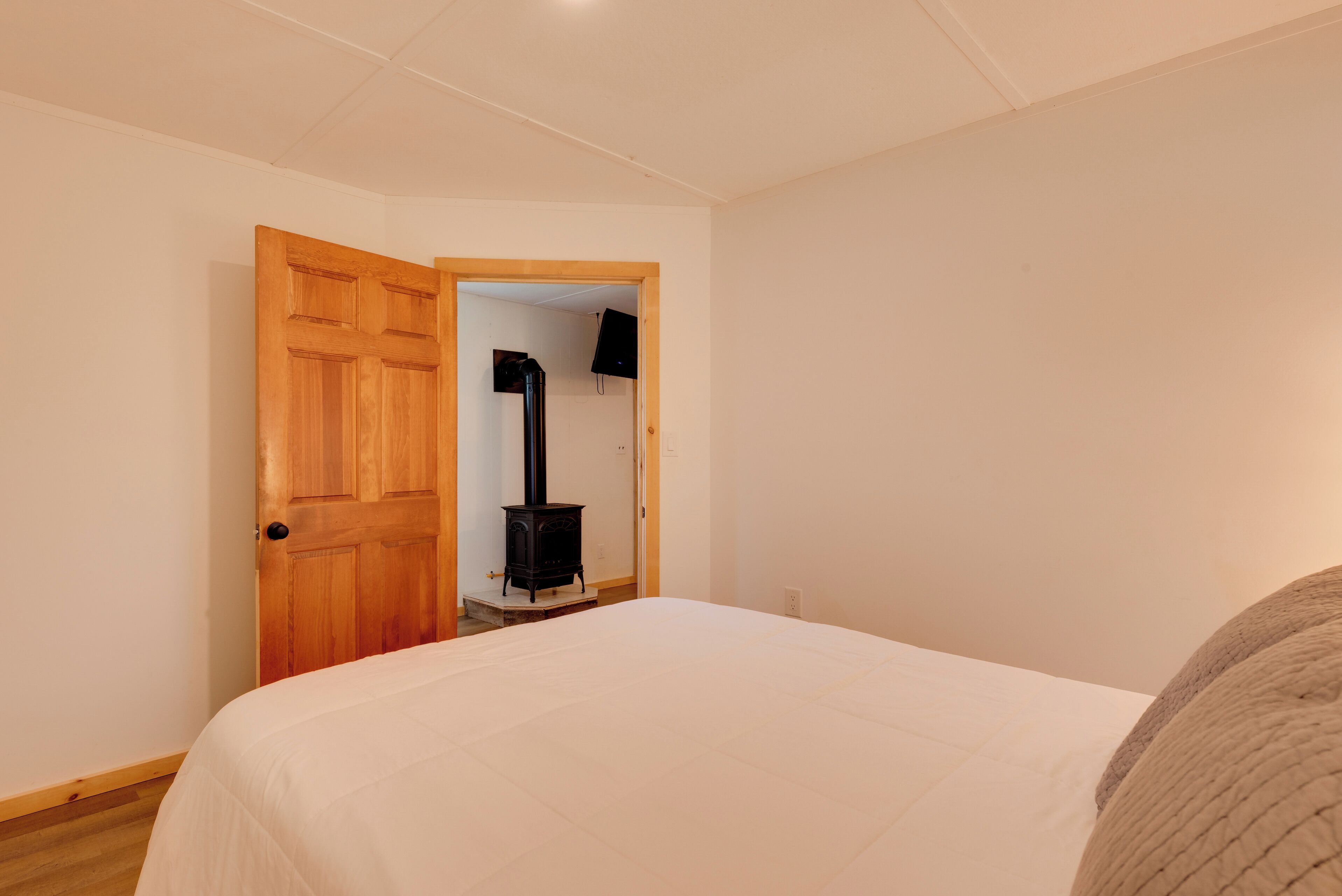 Une chambre à coucher avec un lit, une porte en bois et un radiateur noir à l’arrière-plan.