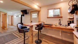 Une cuisine moderne avec des poutres en bois, un coin bar et une fenêtre donnant sur l’extérieur.
