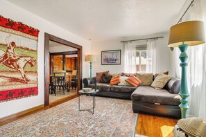 A living room with a sofa, a coffee table, and a rug. There is a painting on the wall and a lamp on a side table. - Family-friendly Albuquerque Home Near Rio Grande! (Albuquerque)