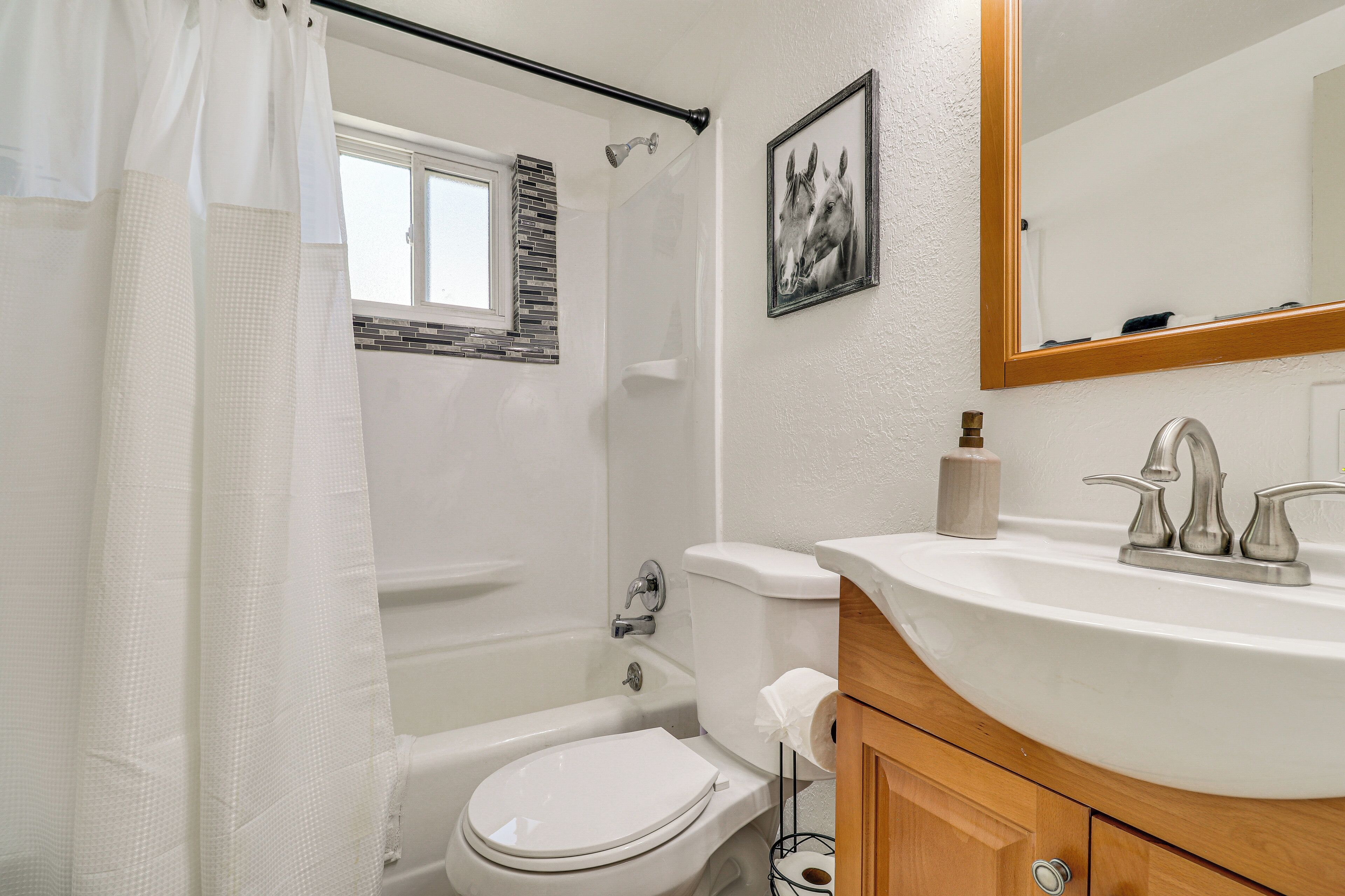 A bathroom with a white toilet, a bathtub, a sink with a mirror, and a shower curtain.