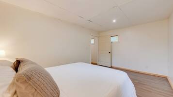 A bedroom with a bed, a door, and a light switch on the wall.