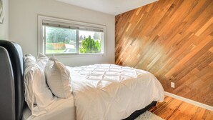 A bedroom with a bed, a window, a ceiling fan, and a wooden wall. - Milwaukie Home w/ Outdoor Dining Space (Milwaukie)