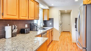 A kitchen with wooden cabinets, a granite countertop, a stainless steel refrigerator, and a dishwasher. - Milwaukie Home w/ Outdoor Dining Space (Milwaukie)