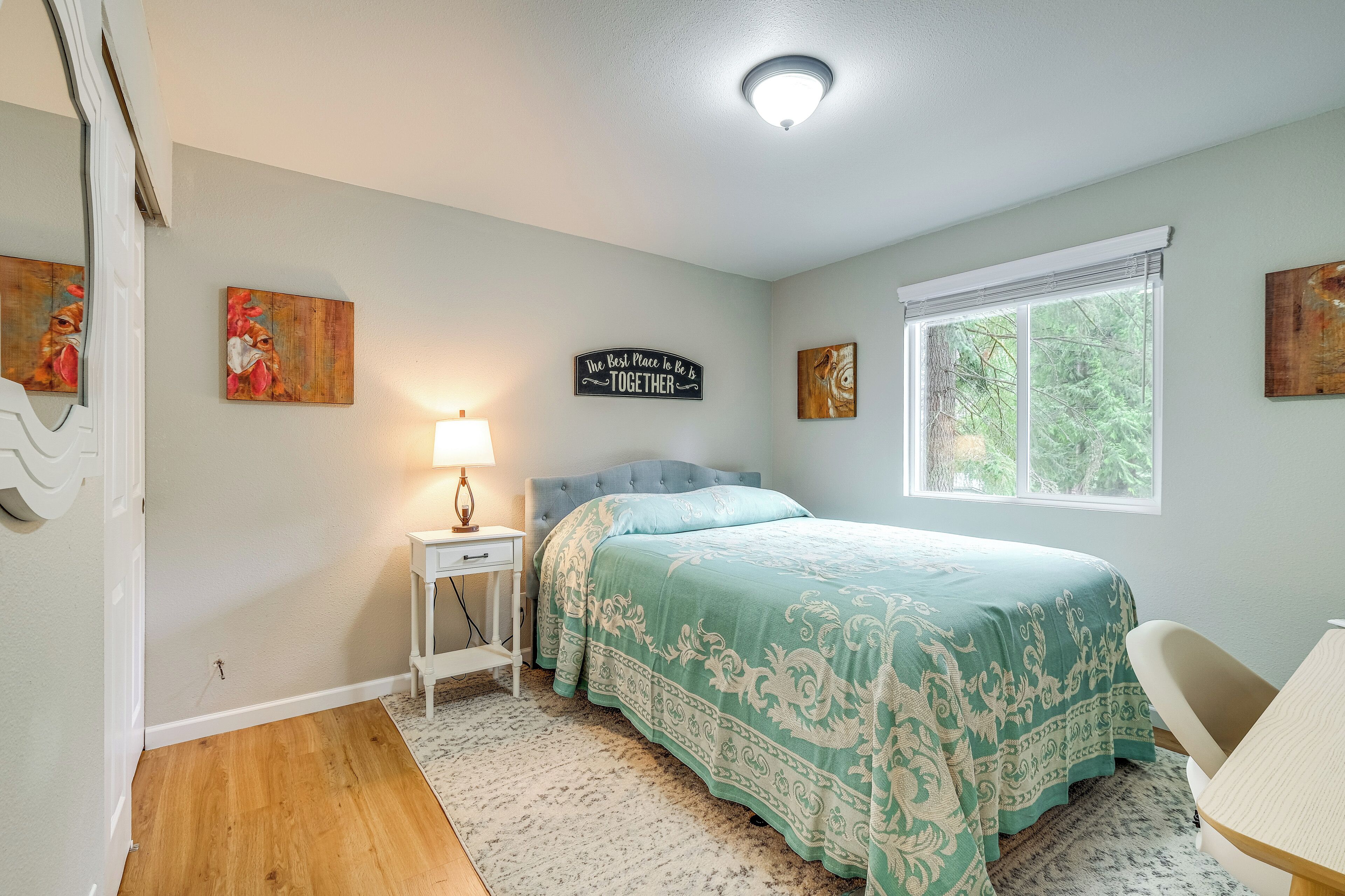 A bedroom with a bed, a nightstand, a lamp, and artwork on the walls.