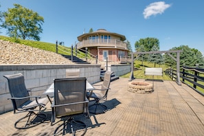 Een terras met buitenmeubilair, een stenen muur en een gebouw met balkon.
