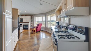 Een ruime keuken met houten vloeren, witte kasten en een gasfornuis.