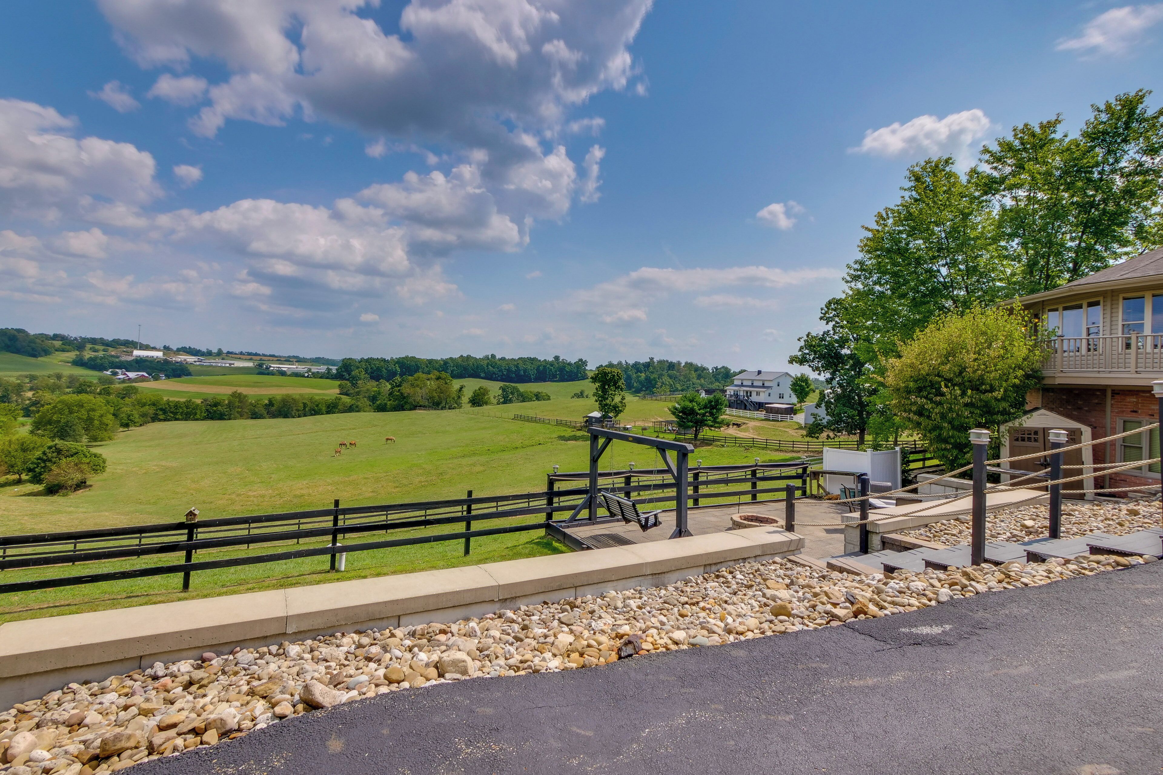 A scenic view of a park with a wooden deck, a metal railing, and a stone pathway.
