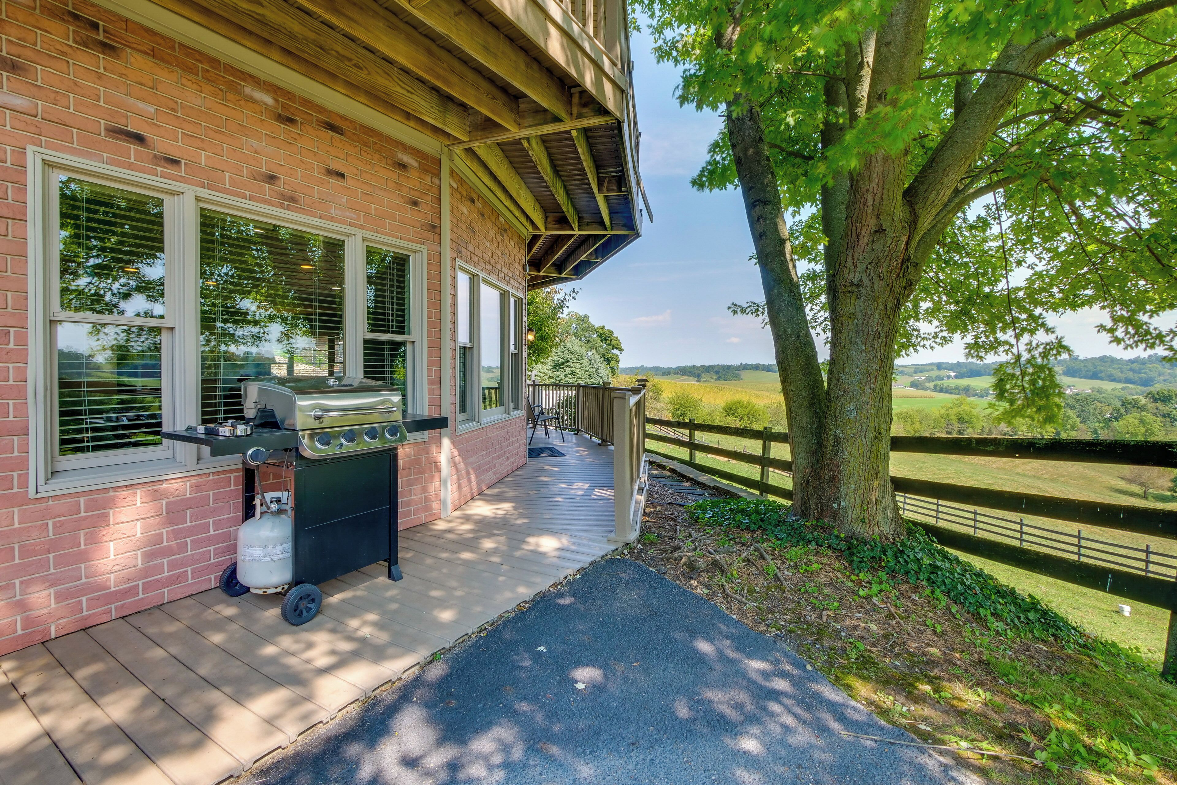 A brick building with a covered porch, a grill, and a view of the countryside.