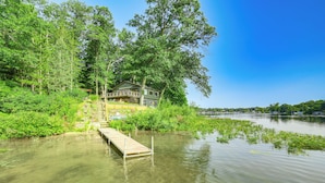 A house by a lake with a wooden dock leading to it. - Private Island: Home in Belding w/ Dock & Grill! (Belding)