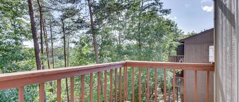 A wooden deck with a railing overlooking a forested area.