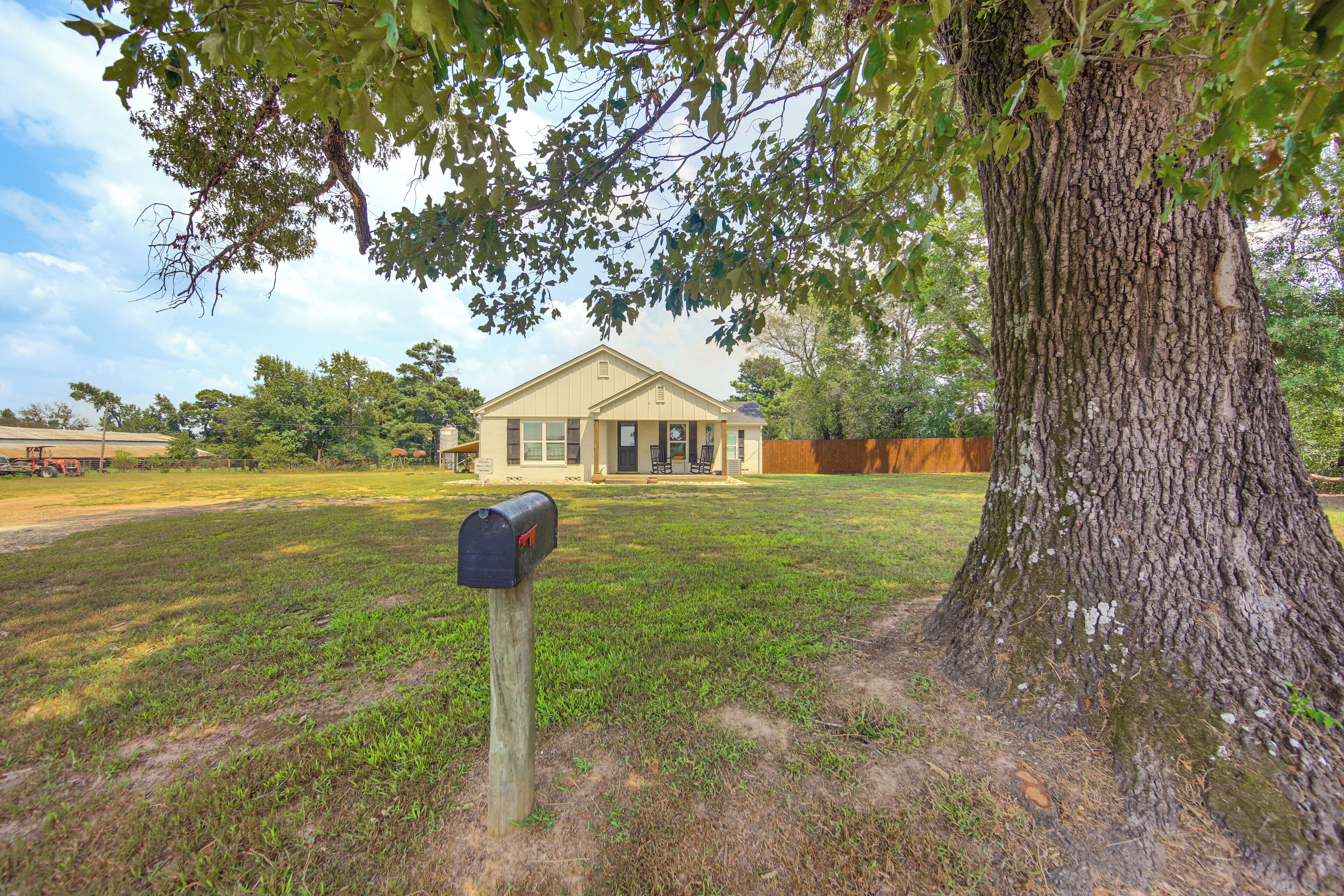 A mailbox in a grassy area with a large tree and a house in the background.