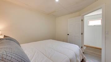 A bedroom with a large bed, a door leading to another room, and a window with a view.