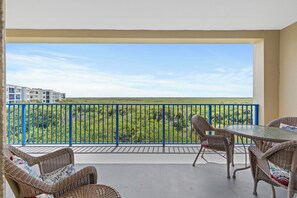 Ein Balkon mit Korbmöbeln und Blick auf eine grüne Landschaft.