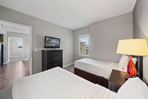 A hotel room with two beds, a TV, a desk, and a lamp. - 6165 Carrier Drive #1001 (Orlando)