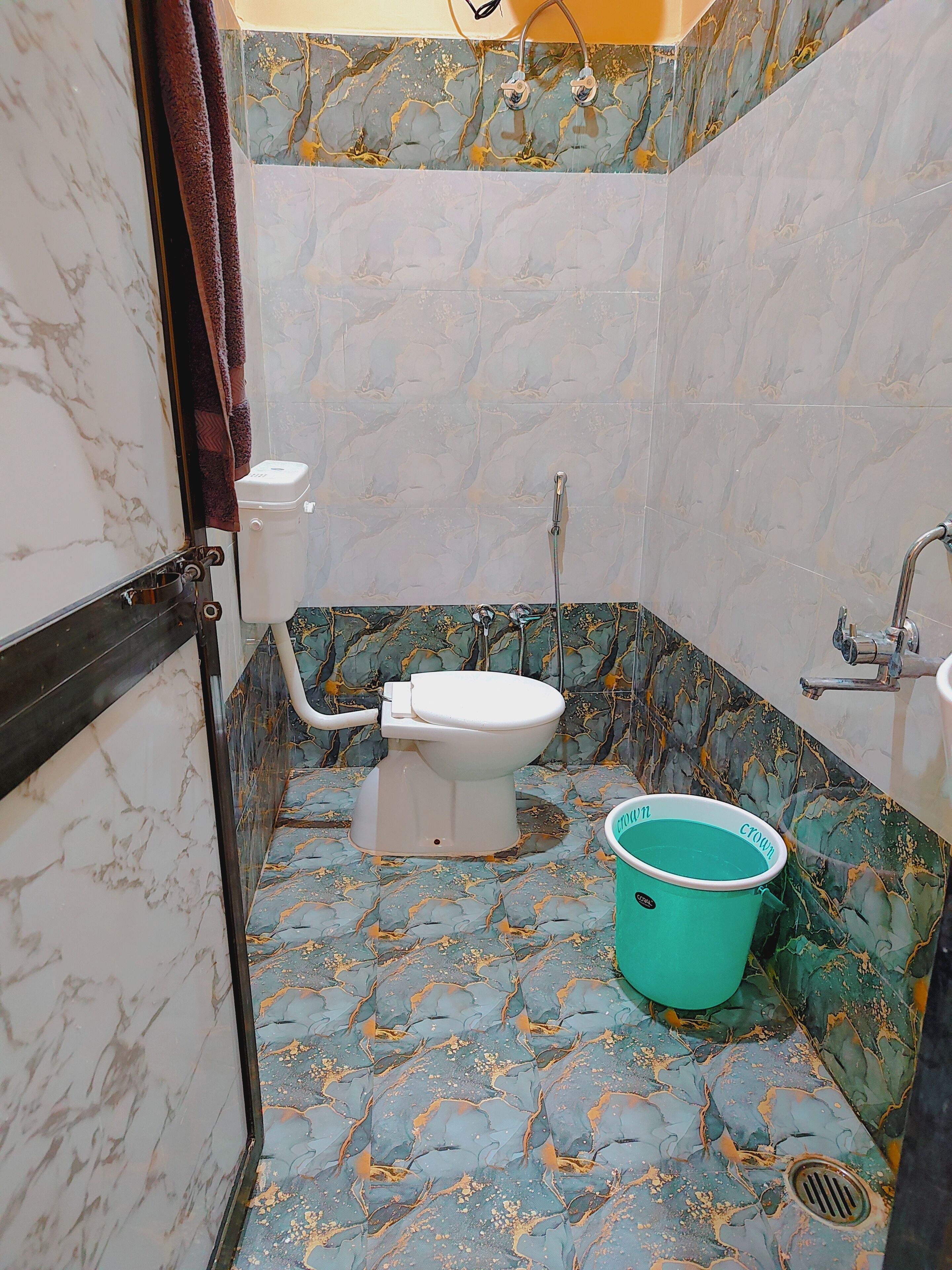 A bathroom with a toilet, a sink, and a bucket.