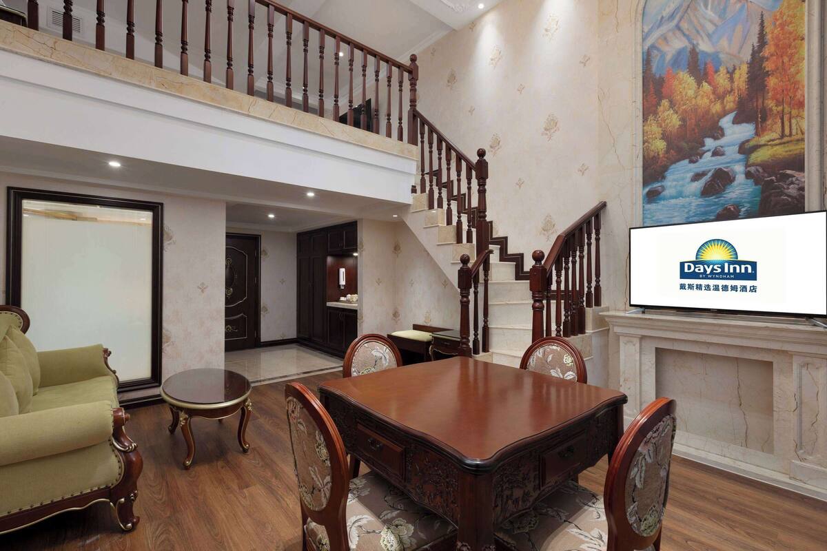 Un espacio habitable amplio con una mesa de comedor de madera, asientos cómodos, una escalera y un mural en la pared.